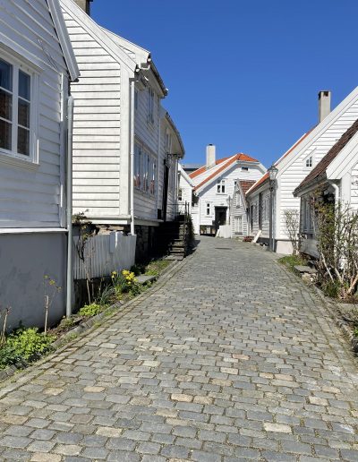 Cobbled street lined with historic white wooden houses in Gamle Stavanger, Norway.